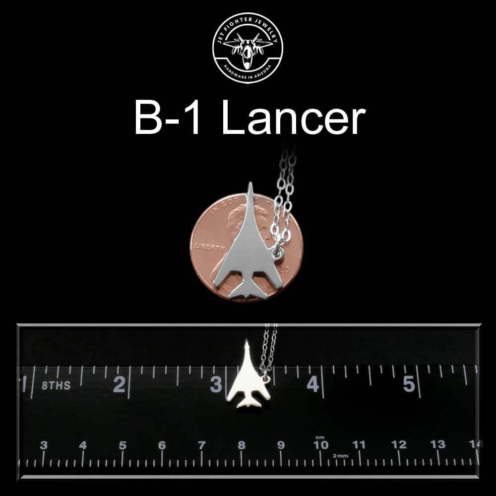 Sterling silver B-1 airplane pendant on a chain with a ruler for scale against a black background, featuring the 'B-1 Lancer' text.