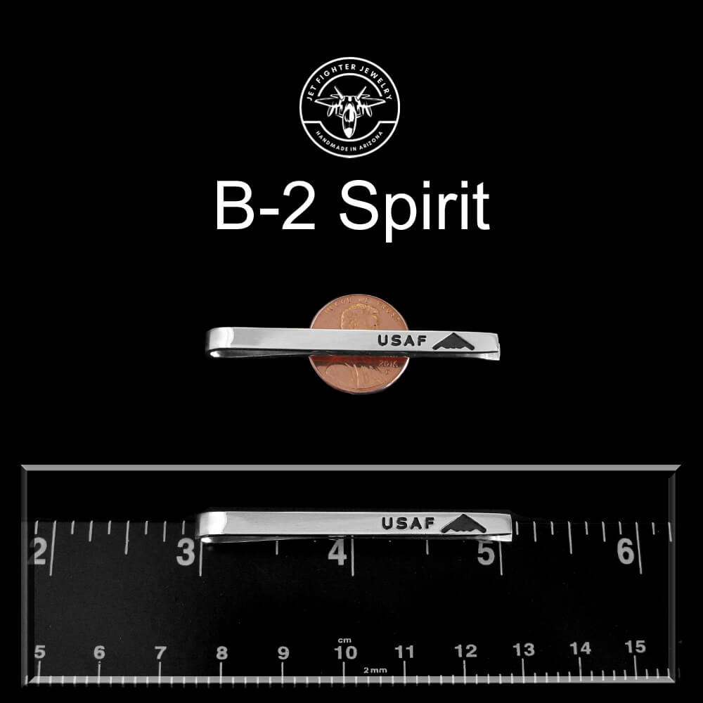 Silver USAF tie clip with a penny and ruler for scale on a black background