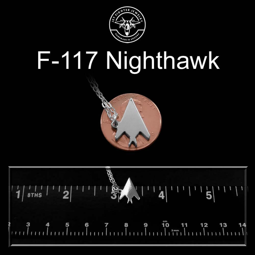 F-117 Nighthawk sterling silver necklace pendant on a coin with a ruler for scale against a black background