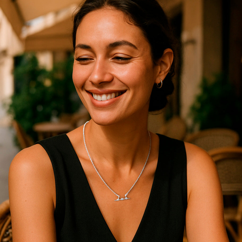 Woman wearing a black sleeveless top and silver SR-71 necklace with a blurred outdoor background