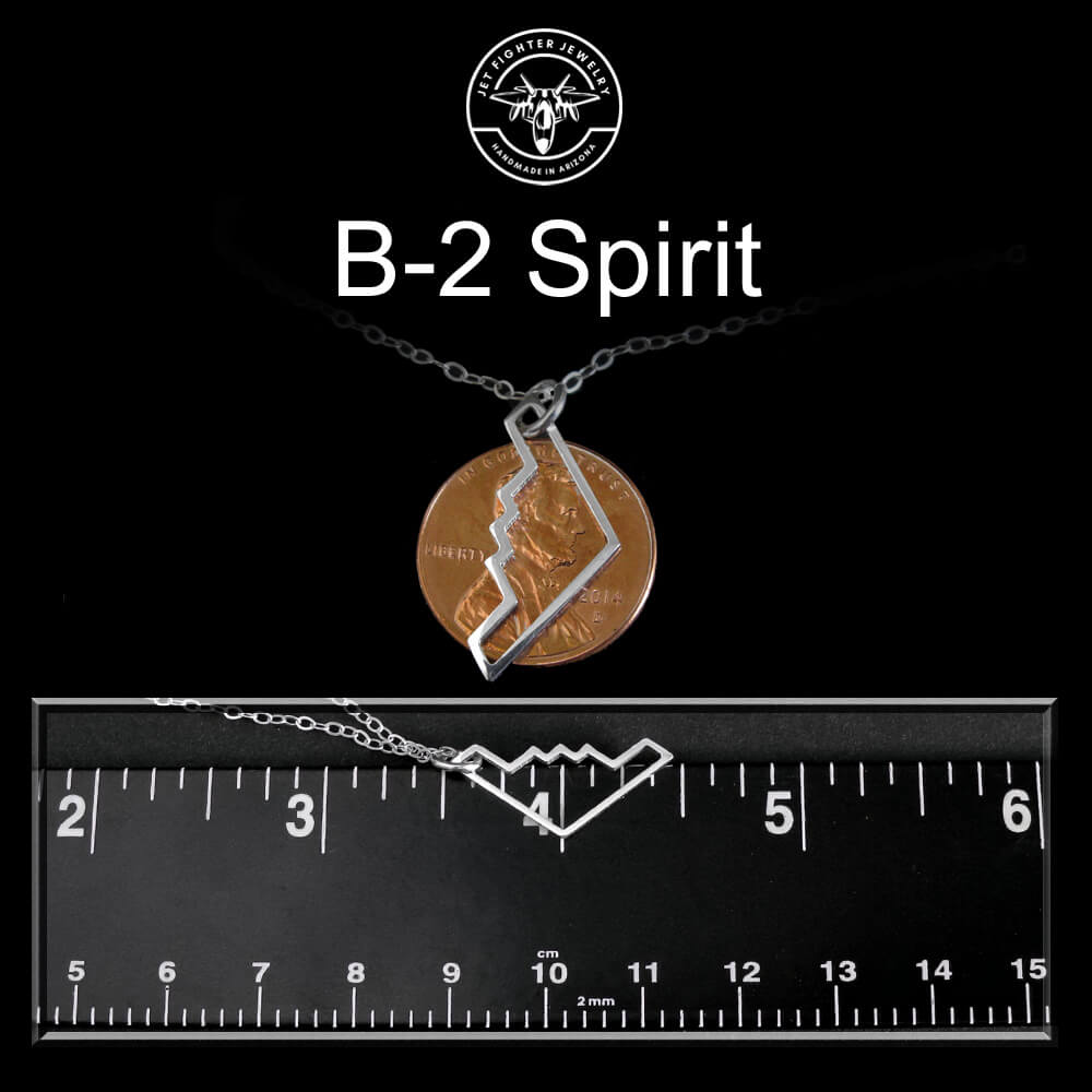 B-2 Bomber Military Jet Jewelry with a penny and silver piece on a black background with a ruler for scale.