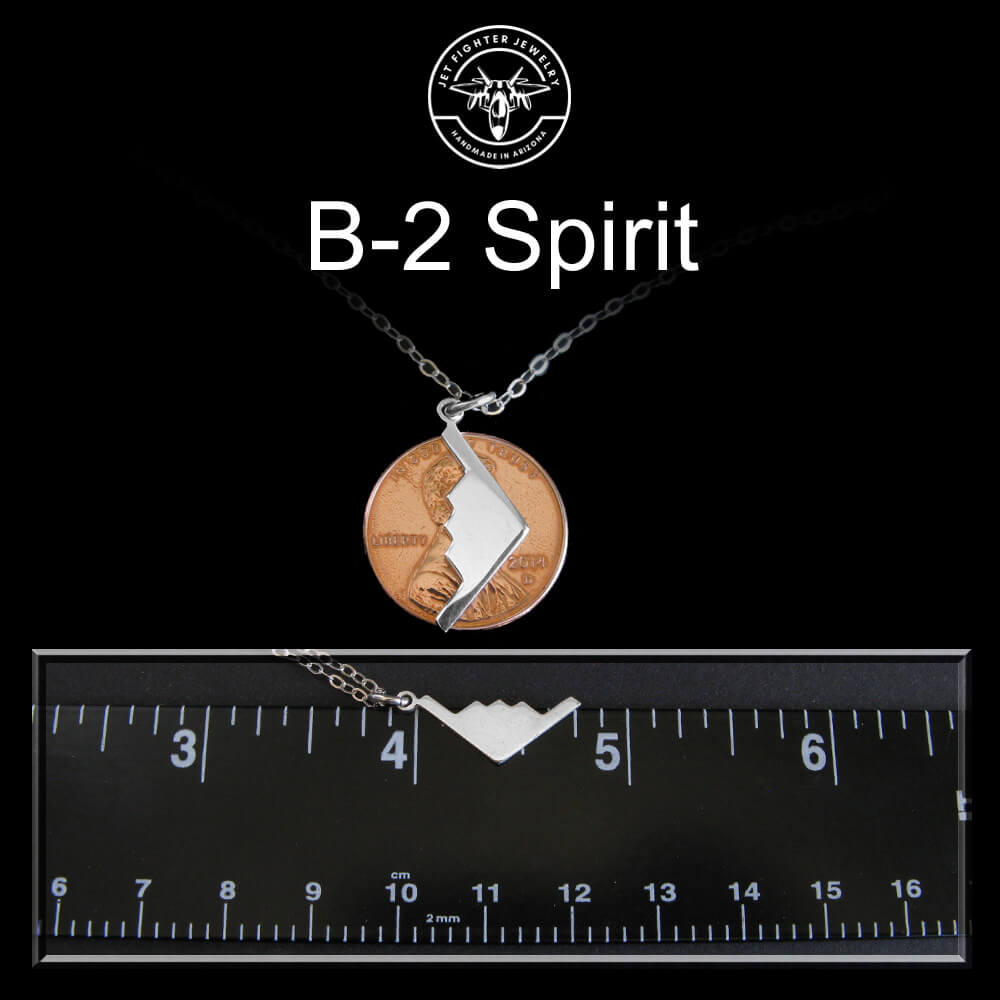 Necklace with a pendant labeled 'B-2 Spirit' on a black background with a ruler for scale.