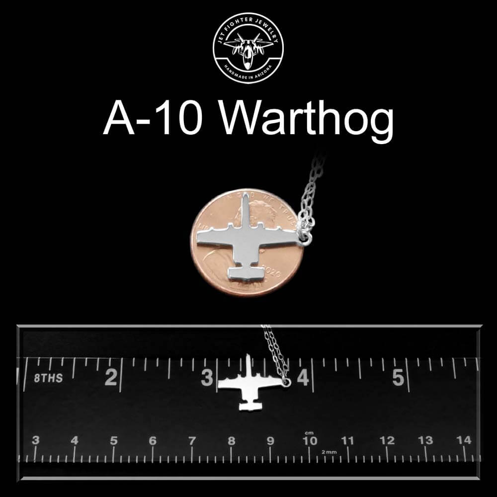 A-10 Warthog jet fighter airplane necklace pendant on a black background with a ruler for scale.