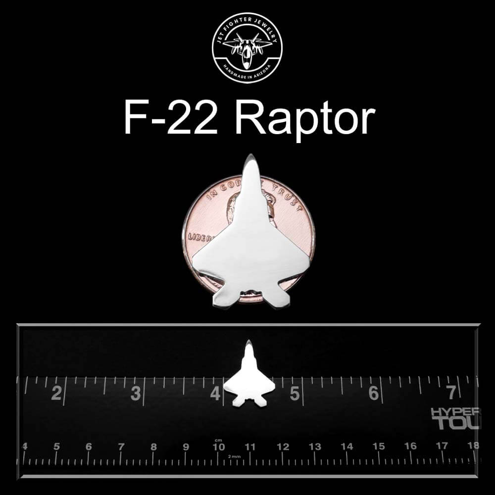 F-22 Raptor tie pin tack on a black background with a ruler and penny for scale.