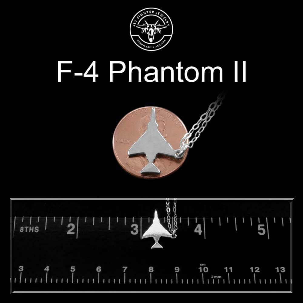 Sterling silver F-4 jet pendant on a chain next to a penny and ruler for scale on a black background.