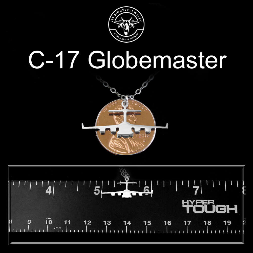 Pendant shaped like a C-17 Globemaster airplane on a black background with a ruler for scale.