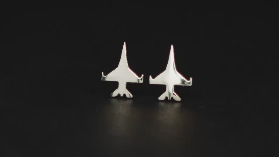 Pair of sterling silver F-16 Viper military jet fighter stud earrings on a turntable with a dark background