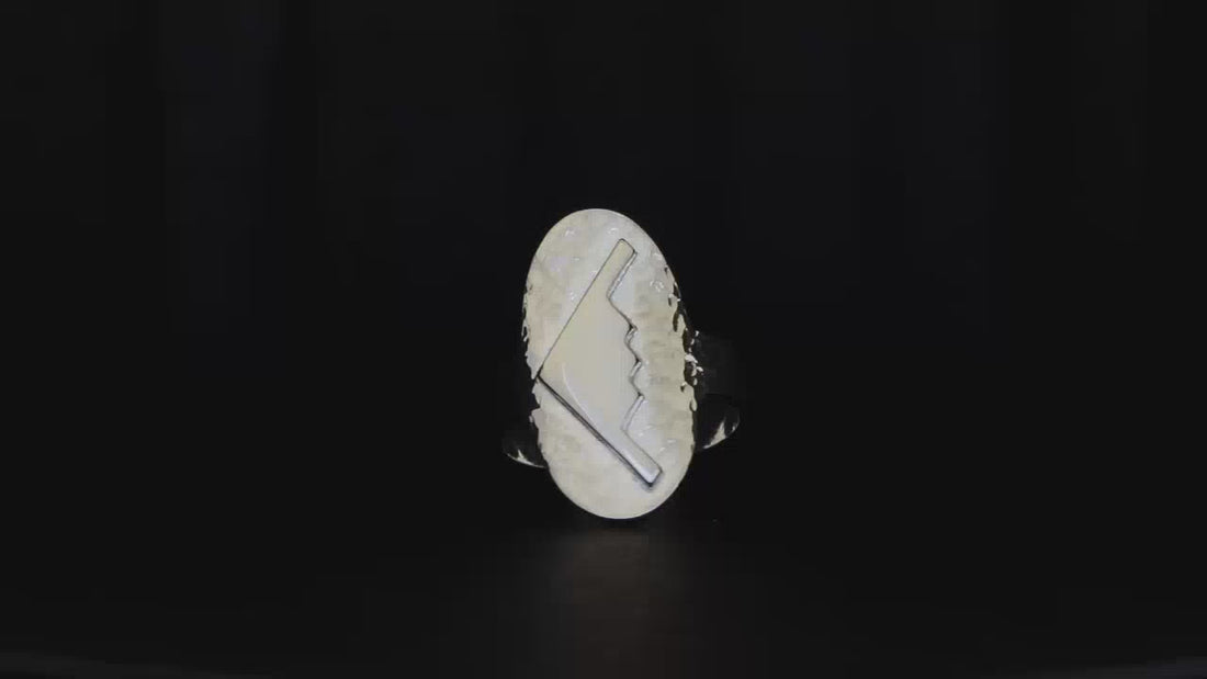 Hammered silver oval ring with a raised B-2 Bomber silhouette on a turntable