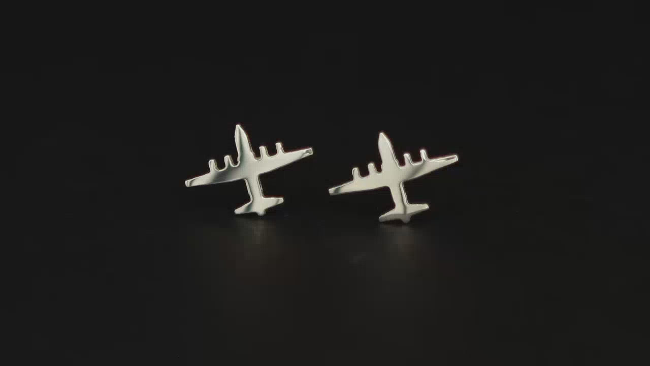 A pair of sterling silver c-130 airplane earrings on a turntable with a dark background