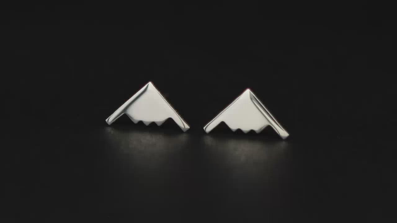 A pair of sterling silver B-2 stud earrings on a turntable with a dark background