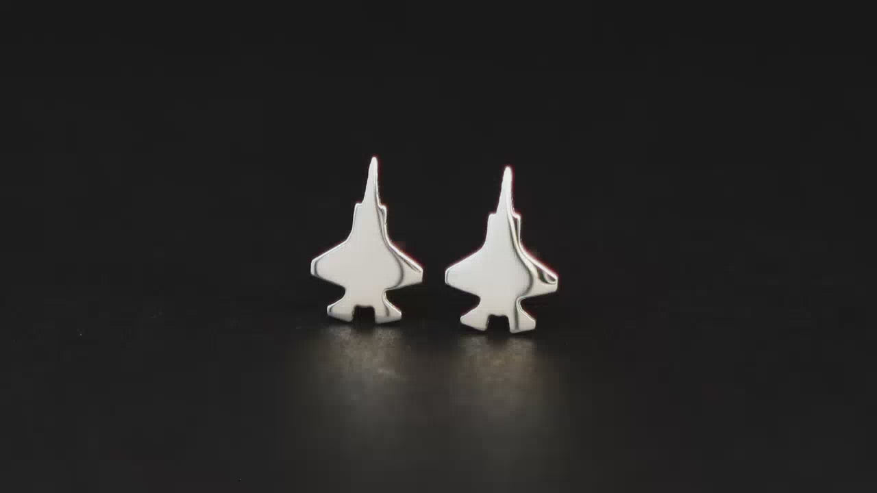 Pair of sterling silver F-35 fighter jet stud earrings on a turntable with a dark background