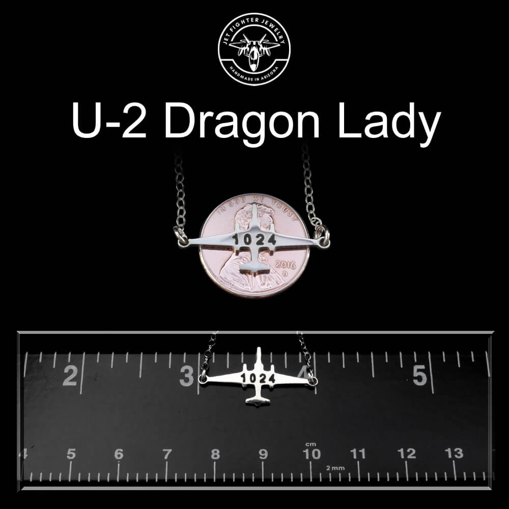 U-2 Dragon Lady necklace with a coin and airplane pendant on a black background, featuring a ruler for scale.